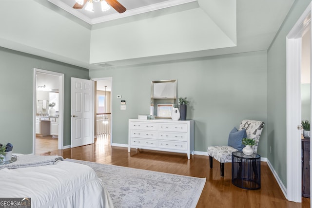 bedroom featuring hardwood / wood-style flooring, a raised ceiling, ceiling fan, and ensuite bath