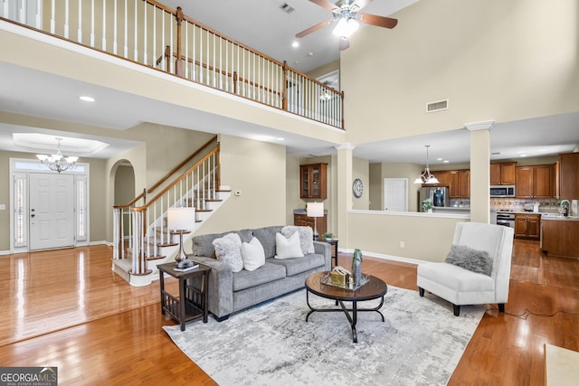 living room with sink, light hardwood / wood-style flooring, ceiling fan, decorative columns, and a high ceiling