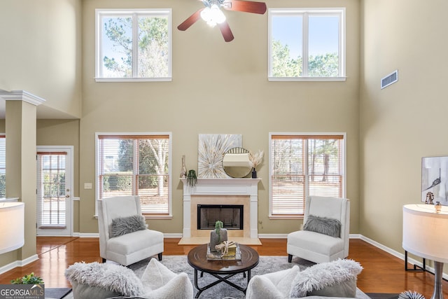 living room with hardwood / wood-style flooring, ceiling fan, a fireplace, and a wealth of natural light