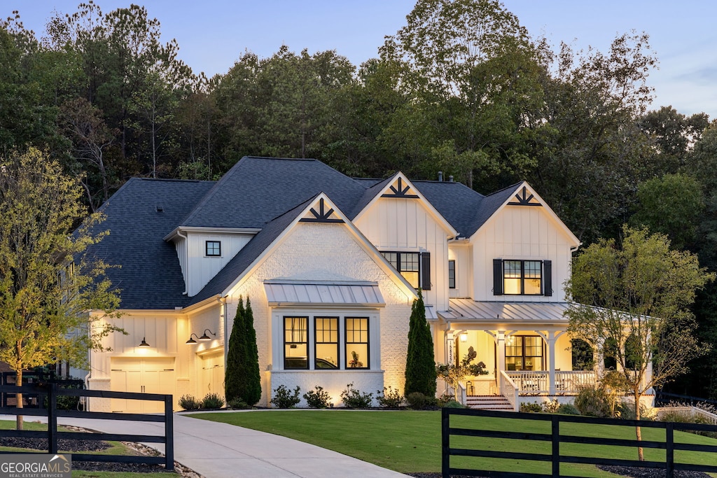 modern farmhouse style home featuring a porch, a garage, and a front yard