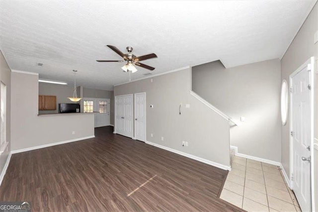 unfurnished living room with dark wood-type flooring, ceiling fan, and a textured ceiling