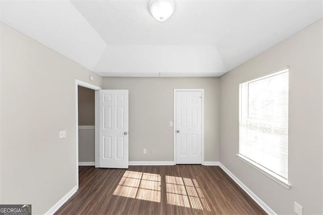 unfurnished room featuring lofted ceiling and dark hardwood / wood-style flooring