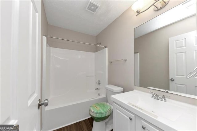 full bathroom featuring vanity, wood-type flooring, washtub / shower combination, and toilet