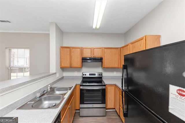 kitchen featuring sink, black fridge, dark hardwood / wood-style flooring, stainless steel range with electric cooktop, and kitchen peninsula