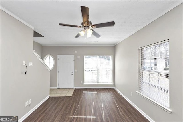 foyer entrance with ceiling fan, ornamental molding, and wood-type flooring