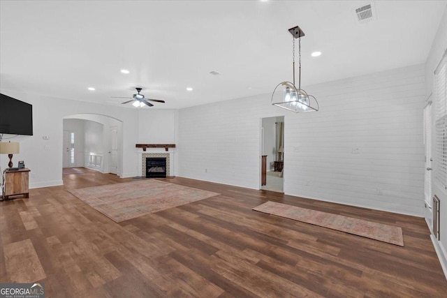 unfurnished living room featuring hardwood / wood-style flooring, ceiling fan, and brick wall