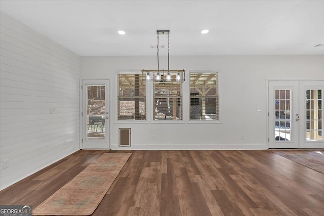 unfurnished dining area with french doors, dark hardwood / wood-style floors, and wood walls