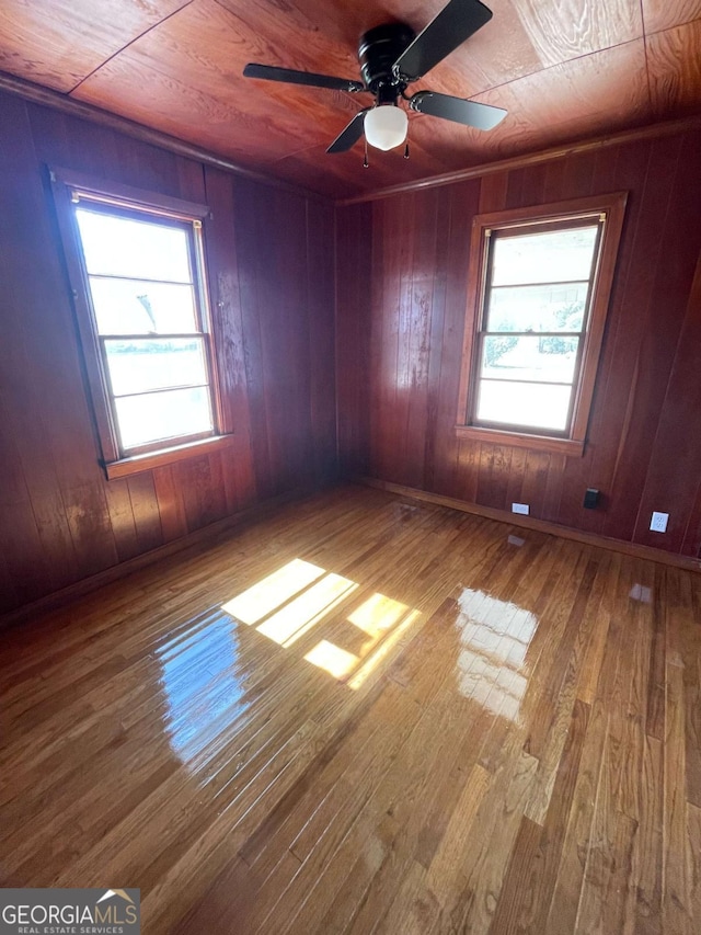 empty room with plenty of natural light, hardwood / wood-style floors, and wood walls