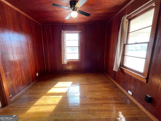 spare room featuring wooden walls, ceiling fan, and light wood-type flooring