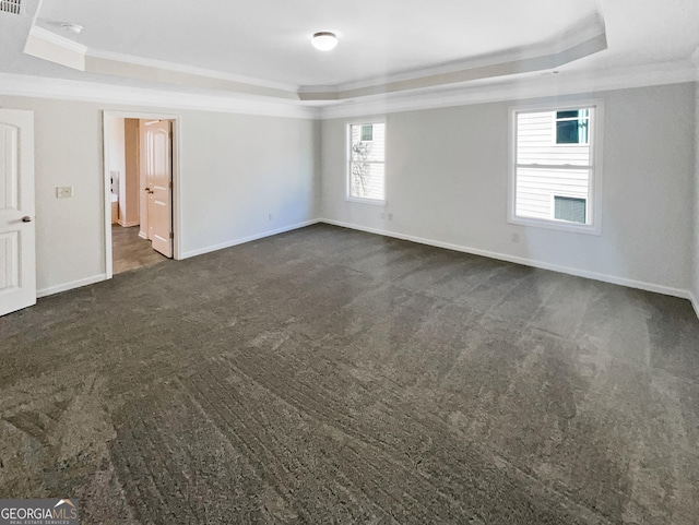 spare room with crown molding, a tray ceiling, and dark carpet