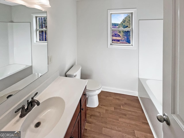 bathroom featuring vanity, a bathing tub, hardwood / wood-style floors, and toilet