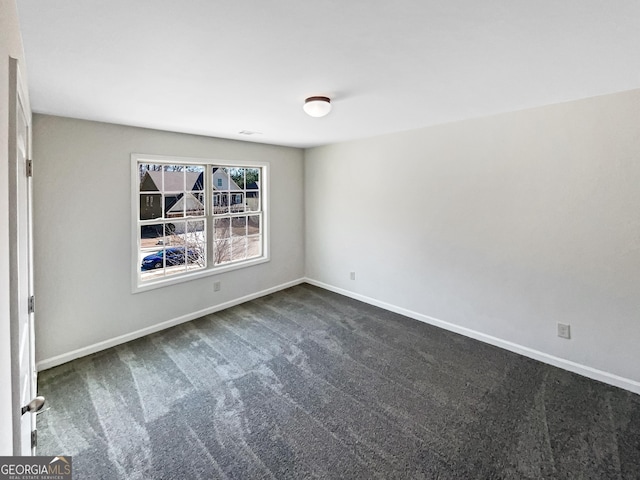 unfurnished room featuring dark colored carpet