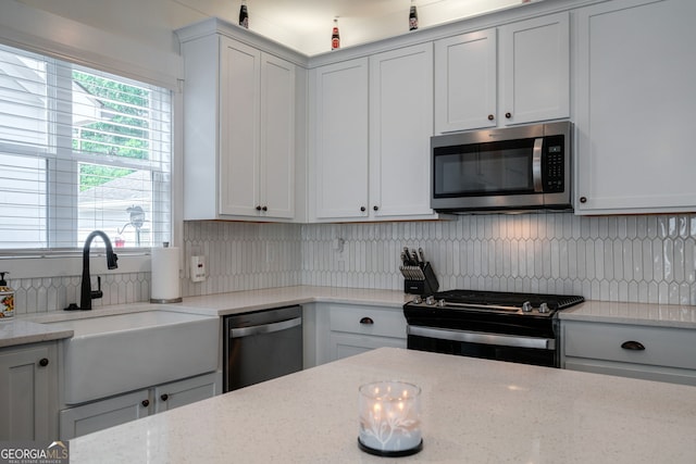 kitchen featuring light stone counters, appliances with stainless steel finishes, sink, and decorative backsplash