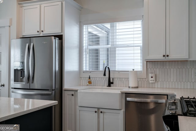 kitchen with stainless steel appliances, tasteful backsplash, sink, and white cabinets