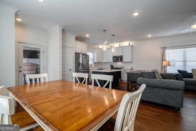 dining space featuring dark wood-type flooring, ornamental molding, and ceiling fan