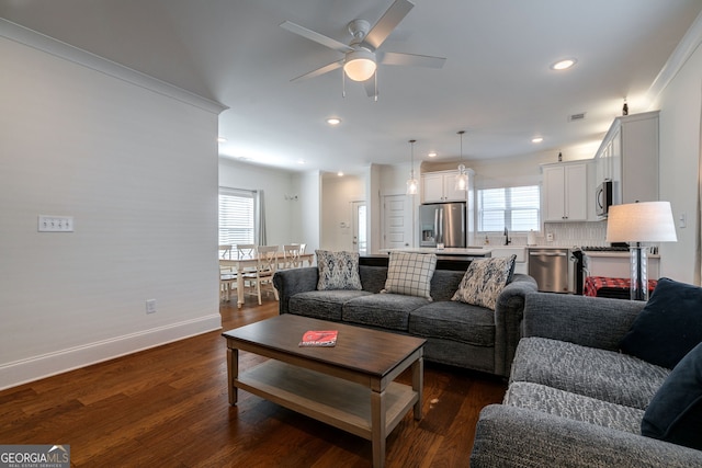 living room featuring dark wood-type flooring, ceiling fan, and a wealth of natural light