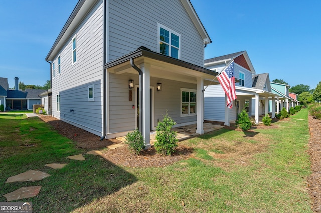 view of home's exterior with covered porch and a lawn