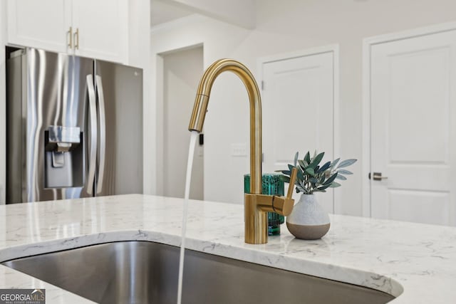 interior details featuring crown molding, light stone countertops, white cabinets, and stainless steel fridge with ice dispenser