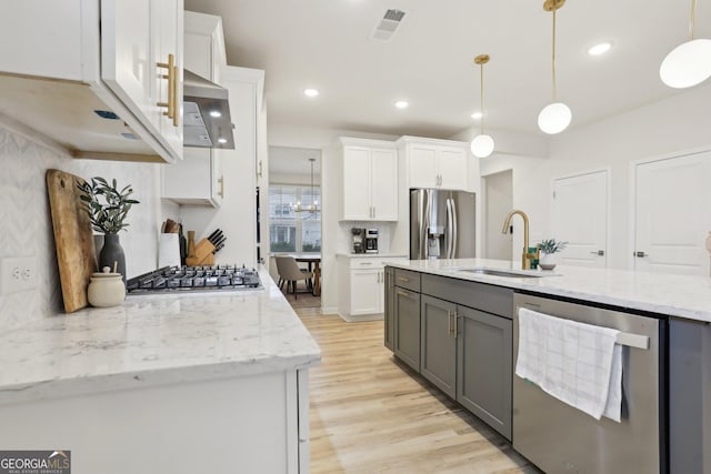 kitchen featuring white cabinetry, sink, decorative light fixtures, and appliances with stainless steel finishes