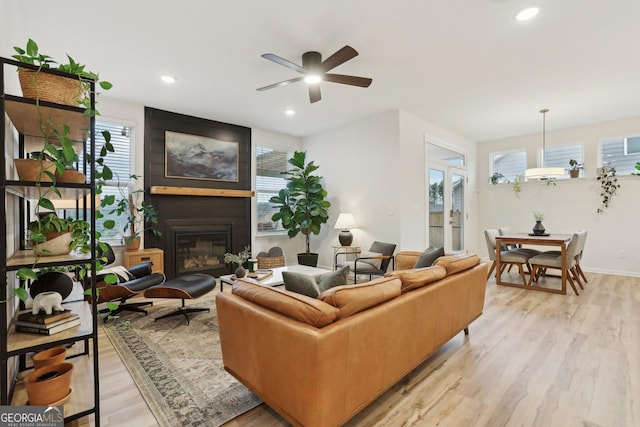 living room featuring ceiling fan, a fireplace, and light hardwood / wood-style floors