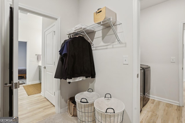 walk in closet with light hardwood / wood-style floors and washer and dryer