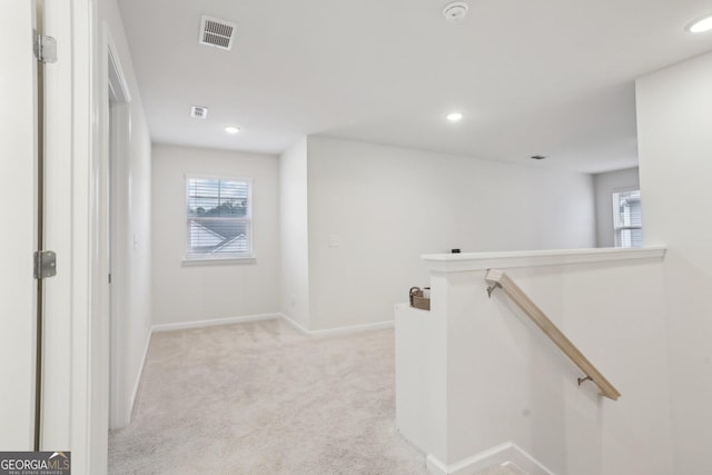 hallway featuring a wealth of natural light and light colored carpet