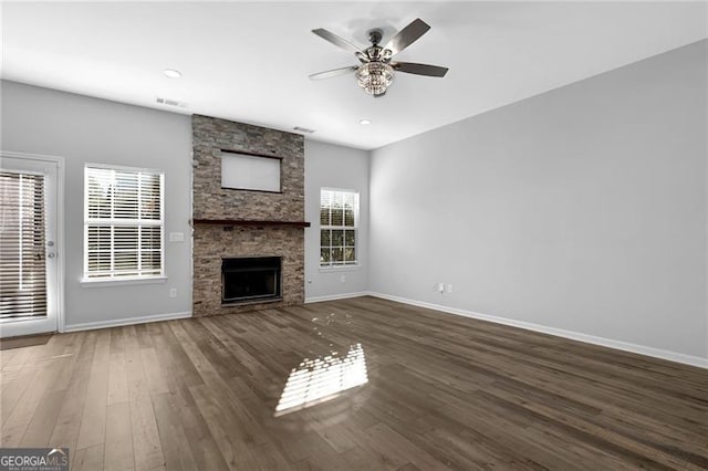 unfurnished living room with a fireplace, visible vents, ceiling fan, wood finished floors, and baseboards