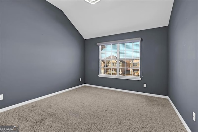 unfurnished room with vaulted ceiling, carpet flooring, and baseboards