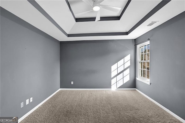 carpeted empty room featuring a raised ceiling, visible vents, and baseboards