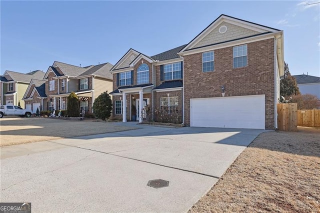 traditional-style home featuring brick siding, an attached garage, fence, a residential view, and driveway