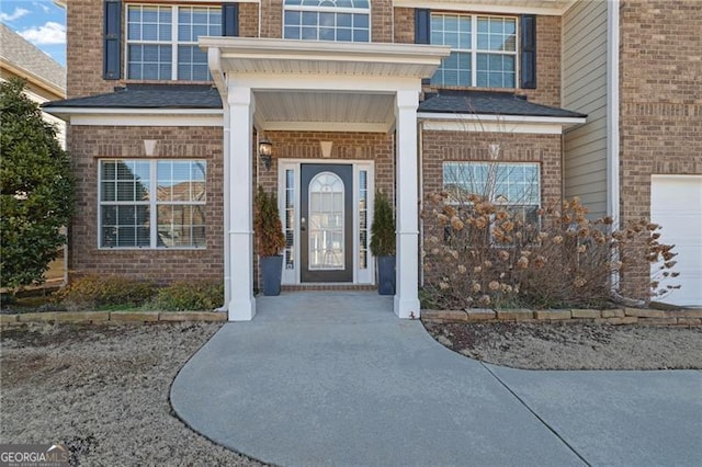 doorway to property with a garage and brick siding