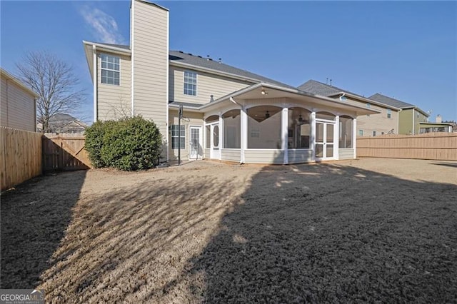 rear view of house featuring a sunroom, a fenced backyard, and a chimney