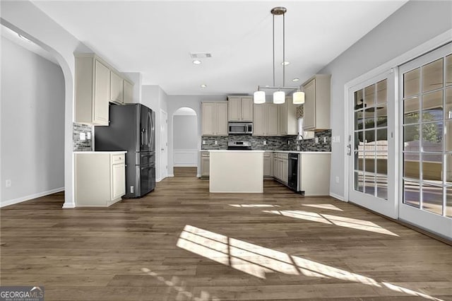 kitchen with stainless steel appliances, arched walkways, a kitchen island, and backsplash