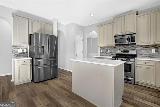 kitchen with appliances with stainless steel finishes, arched walkways, cream cabinetry, and light countertops