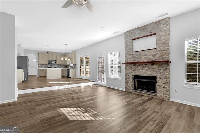 unfurnished living room featuring baseboards, a fireplace, visible vents, and wood finished floors