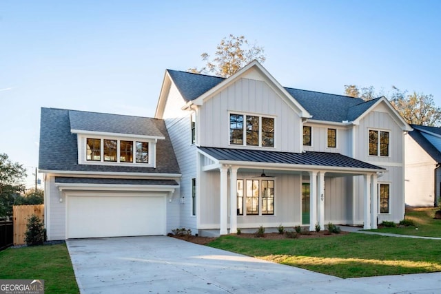 modern farmhouse featuring a garage, a porch, and a front lawn