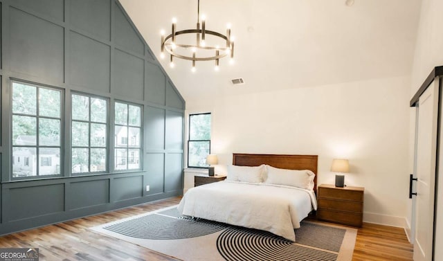 bedroom featuring a chandelier, high vaulted ceiling, and light hardwood / wood-style flooring