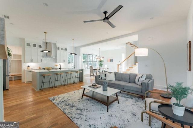 living room featuring sink, ceiling fan with notable chandelier, and light hardwood / wood-style floors