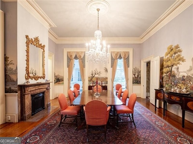 dining area with an inviting chandelier, hardwood / wood-style floors, crown molding, and a high end fireplace