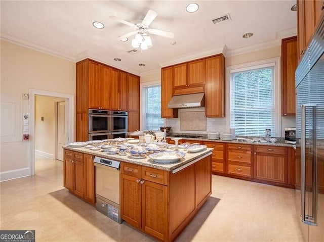 kitchen featuring light stone countertops, appliances with stainless steel finishes, ventilation hood, and a kitchen island