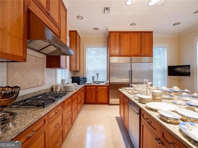 kitchen with backsplash, ornamental molding, light stone countertops, and appliances with stainless steel finishes