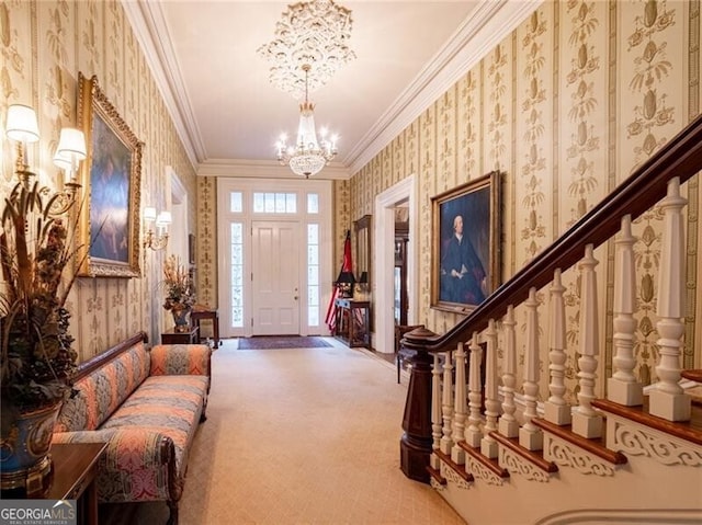 carpeted foyer entrance with ornamental molding and a chandelier