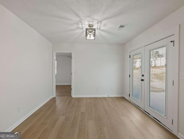 interior space with french doors, light hardwood / wood-style flooring, and a textured ceiling