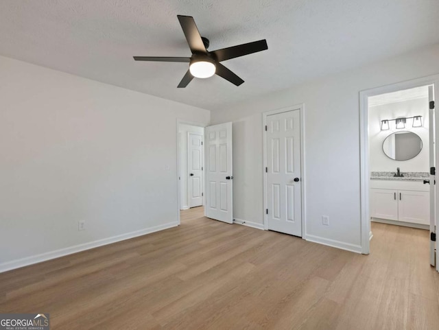 unfurnished bedroom with sink, ensuite bath, ceiling fan, light hardwood / wood-style floors, and a textured ceiling