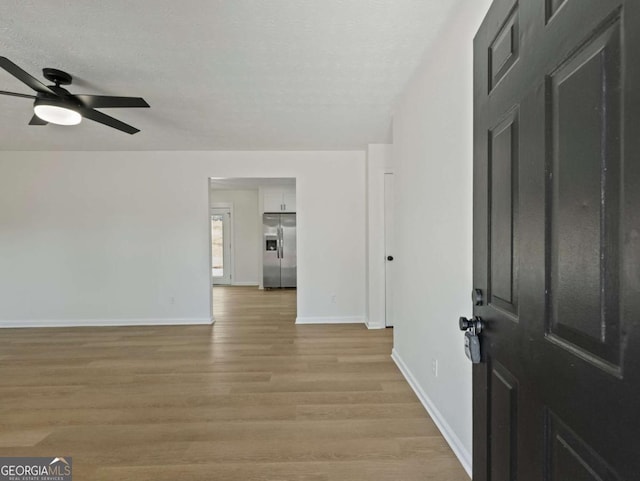 interior space featuring ceiling fan, a textured ceiling, and light wood-type flooring