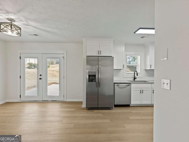 kitchen with sink, white cabinetry, stainless steel appliances, tasteful backsplash, and light wood-type flooring