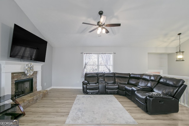 living room with ceiling fan, lofted ceiling, light wood-type flooring, and a fireplace