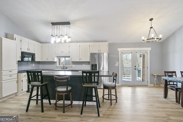 kitchen featuring pendant lighting, stainless steel fridge, vaulted ceiling, and white cabinets