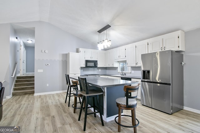 kitchen with vaulted ceiling, white cabinets, hanging light fixtures, stainless steel fridge with ice dispenser, and light wood-type flooring