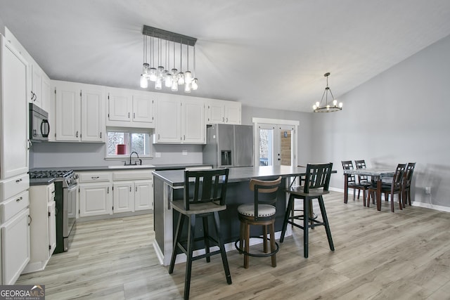 kitchen with hanging light fixtures, stainless steel appliances, white cabinets, and a kitchen island